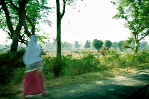 Image of blurred Indian woman walking alongside country road, India