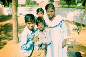 Four Indian school children smiling at camera in school yard in the Indian countryside